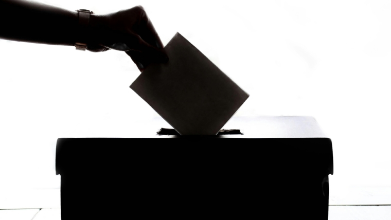 elections, hand placing the voting sheet inside the ballot